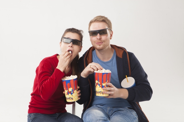 映画館でポップコーンを食べるカップル